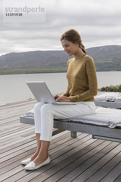 Schöne Frau mit Laptop am Seeufer
