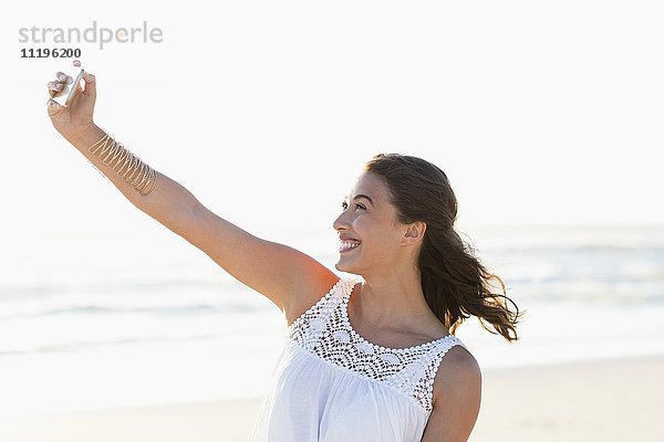 Attraktive junge Frau,  die Selfie mit Smartphone am Strand nimmt