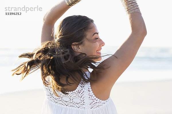 Fröhliche junge Frau,  die am Strand posiert.