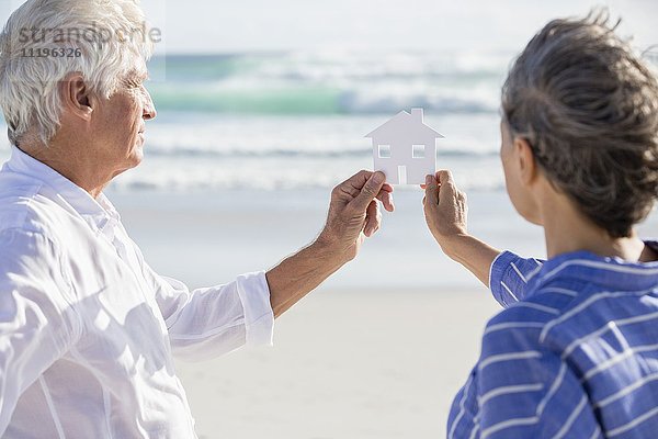 Nahaufnahme eines Paares mit einem Papierhaus am Strand