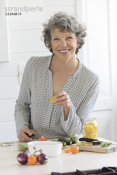 Glückliche Frau beim Zubereiten von Speisen in der Küche