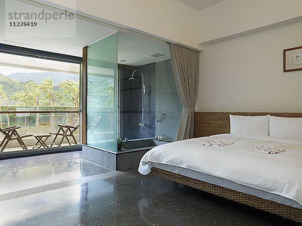 Modernes Schlafzimmer mit Glasdusche und Außenterrasse