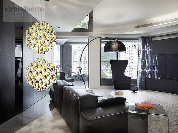 Schwarzes Ledersofa und flippige Lampe in einem modernen Wohnzimmer