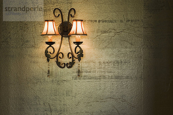 Schmiedeeiserne Lampe auf goldfarbener strukturierter Wand