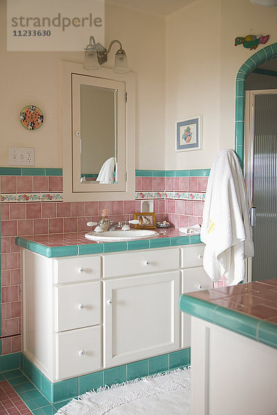 Waschbecken und Tresen in einem rosa und blaugrün gefliesten Badezimmer