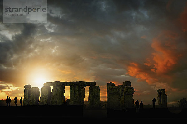Silhouette von Menschen bei Sonnenuntergang in Stonehenge,  England,  Vereinigtes Königreich