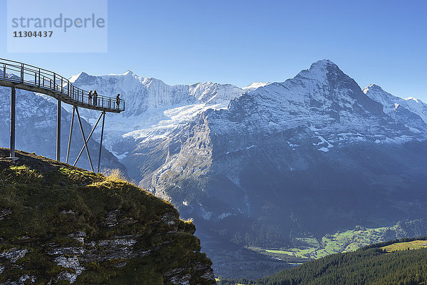 Gipfelweg und Aussichtsplattform mit dem Namen First Cliff Walk auf dem Gipfel des First oberhalb von Grindelwald,  Berner Oberland,  Schweiz. Oberhalb der Plattform die Berge Kleines Fiescherhorn (links) und Grosses Fiescherhorn und rechts Eiger und Jungfrau.