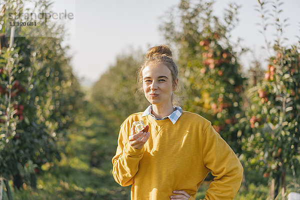 Junge Frau beim Essen eines Apfels im Apfelgarten