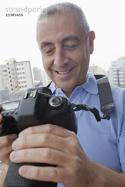 Hispanischer Mann,  der ein Foto auf einer Digitalkamera untersucht