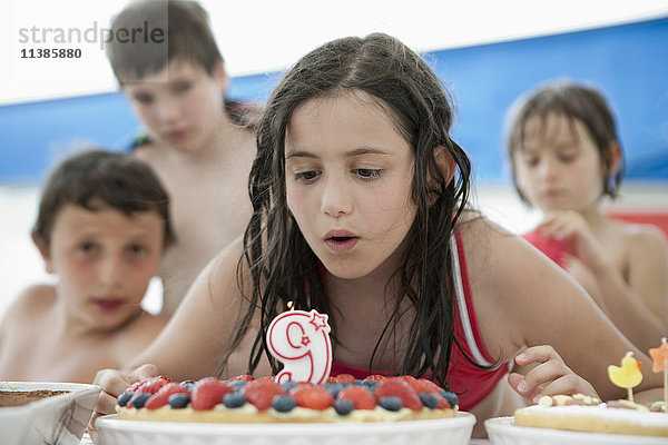 Kaukasisches Mädchen löscht die Kerze auf dem Geburtstagskuchen