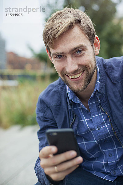 Mann mit Smartphone im Freien,  lächelnd,  Portrait