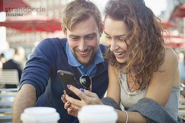 Paar,  das sich das Smartphone gemeinsam im Freien anschaut