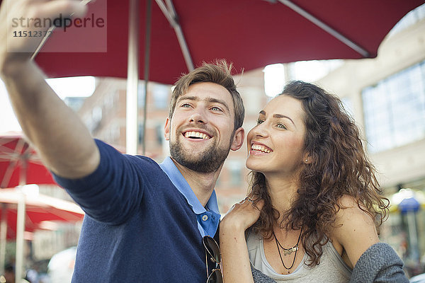 Pärchen posieren für einen Selfie in einem Outdoor-Café