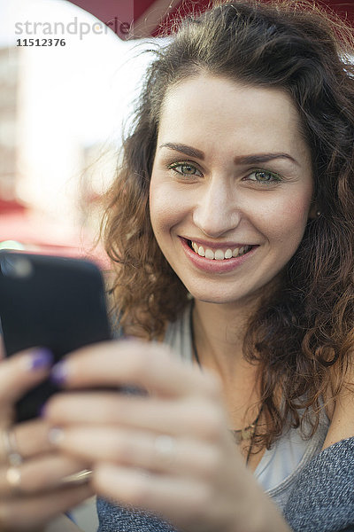 Junge Frau mit Smartphone,  lächelnd,  Portrait