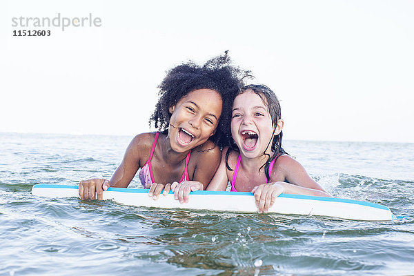 Mädchen spielen mit Bodyboard im Wasser