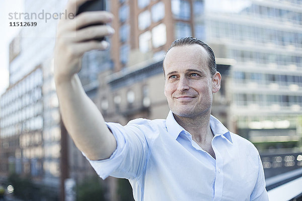 Mann,  der ein Handy benutzt,  um einen Selfie zu nehmen.