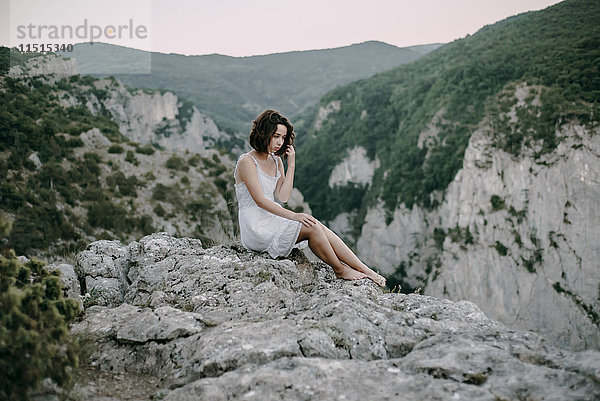Nachdenkliche kaukasische Frau auf einem Berg sitzend