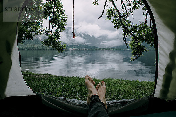Füße eines Mannes im Campingzelt am See