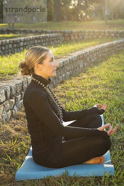 Kaukasische Frau meditiert im Park