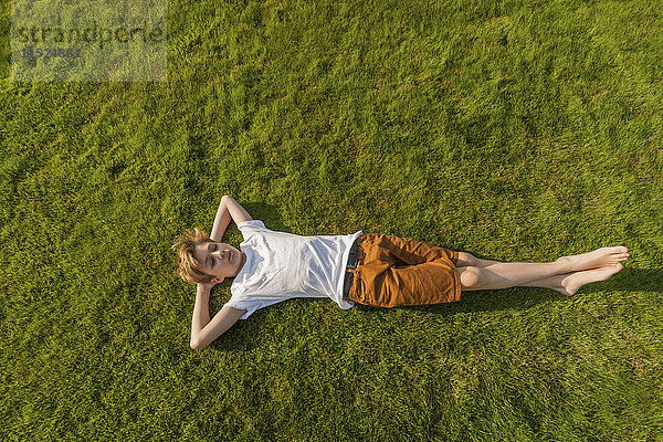 Teenager-Junge im Gras liegend