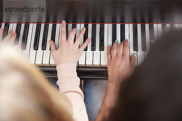 Nahaufnahme von zwei Mädchen,  die zusammen Klavier spielen