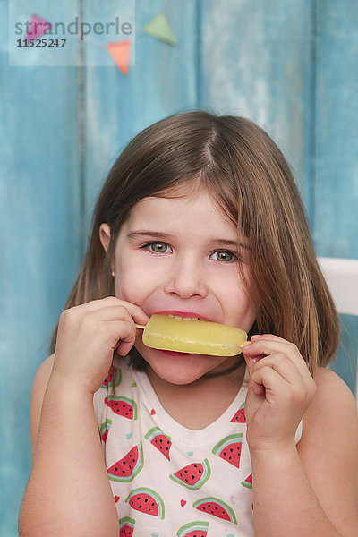 Porträt eines kleinen Mädchens beim Essen von Zitroneneis-Lolly