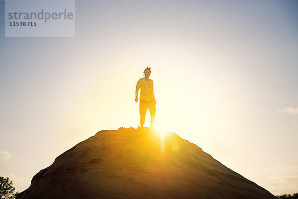 Mann steht auf dem Hügel gegen Sonnenuntergang