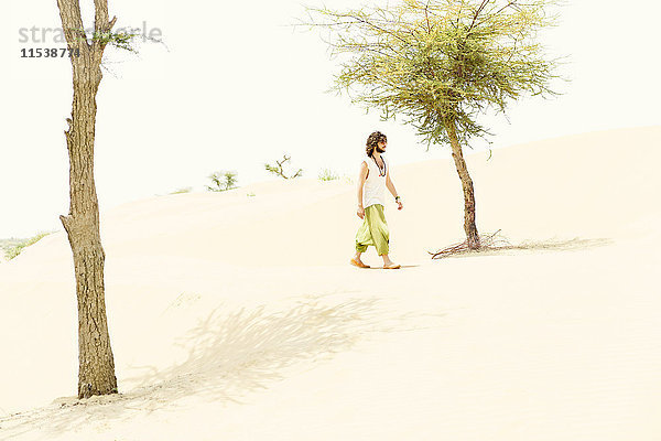 Ein Mann,  der allein in der Wüste spazieren geht.