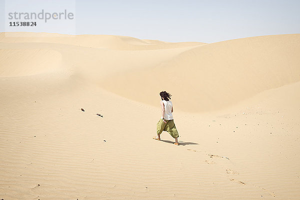 Ein Mann,  der allein in der Wüste spazieren geht.