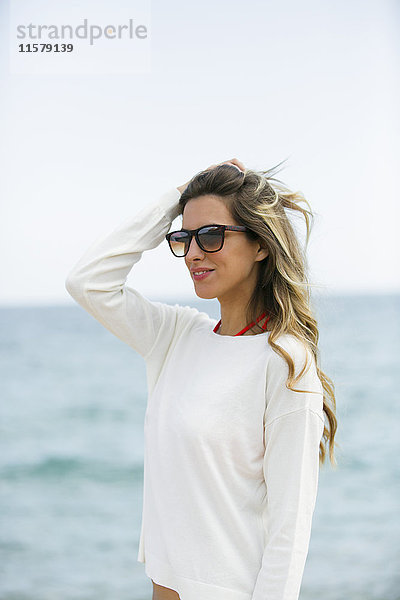 Hübsche blonde Frau mit Sonnenbrille am Strand