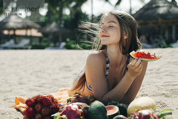 Kaukasische Frau isst Wassermelone am Strand