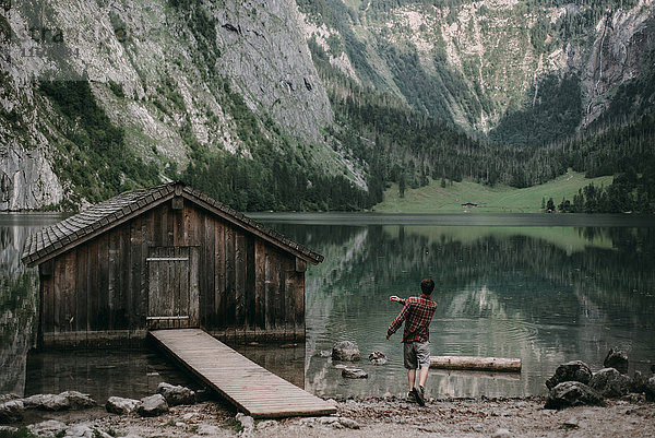 Kaukasischer Mann,  der Steine in einem Bergsee springt