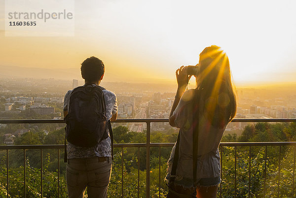 Kaukasisches Paar beim Fotografieren einer malerischen Aussicht auf eine Stadtlandschaft