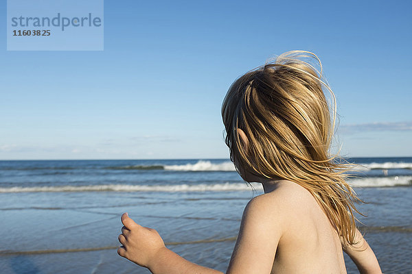 Wind weht Haare eines kaukasischen Mädchens am Strand