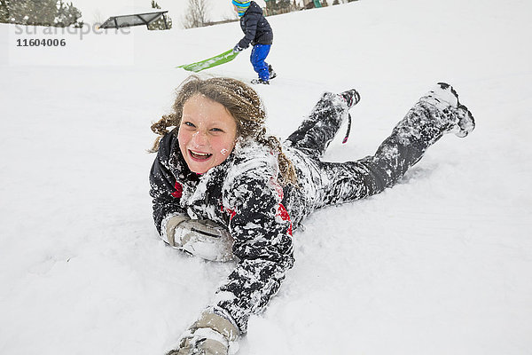Lachendes Mädchen im Schnee liegend im Winter