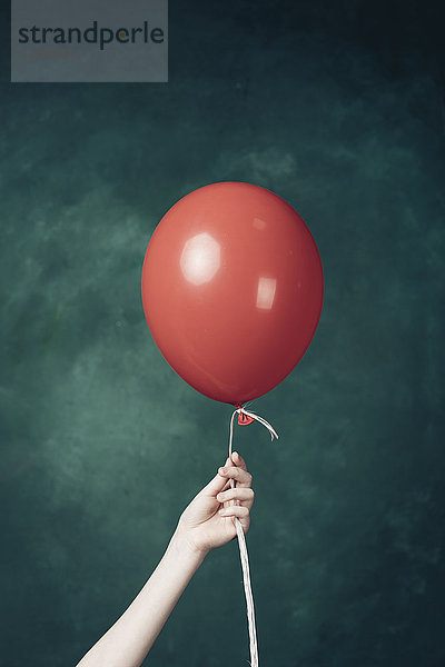 Hand hält roten Luftballon