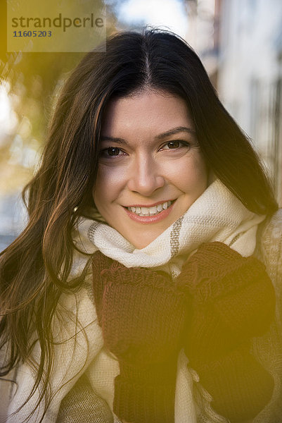 Lächelnde kaukasische Frau mit Handschuhen und Schal