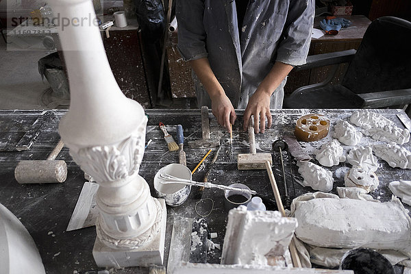 Die Hände eines kaukasischen Bildhauers halten Werkzeuge