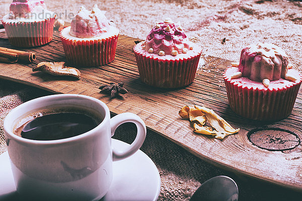 Cupcakes auf Zutaten auf Holztablett mit Kaffee