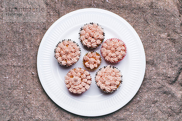 Nahaufnahme von Cupcakes mit rosa Zuckerguss auf einem Teller