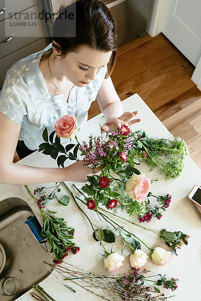 Frau arrangiert Blumen am Tisch