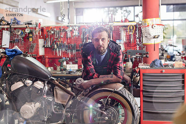 Porträt seriöser,  selbstbewusster Motorradmechaniker in der Werkstatt