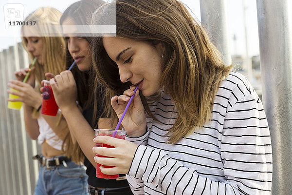 Junge Frau und ihre Freunde beim Trinken von Getränken im Freien