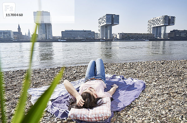 Deutschland,  Köln,  junge Frau entspannt am Rhein