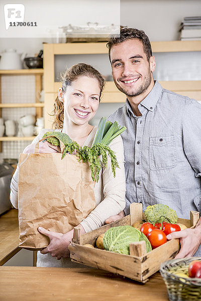 Lächelndes Paar mit Gemüsekiste in der Küche