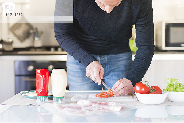 Mann hackt Tomaten in der Küche
