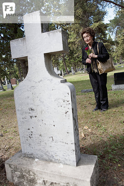 Eine Frau besucht ein Grab auf einem Friedhof; Edmonton,  Alberta,  Kanada .
