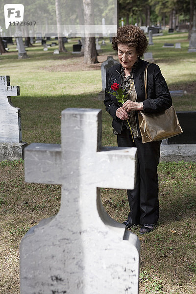 Eine Frau besucht ein Grab auf einem Friedhof; Edmonton,  Alberta,  Kanada .