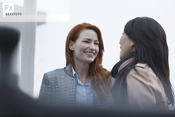 Lächelnde Geschäftsfrauen beim Reden im Freien