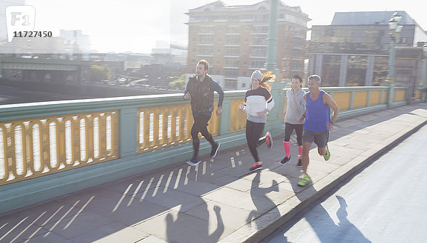 Läuferinnen und Läufer auf einer sonnigen Stadtbrücke